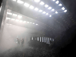 Miembros del cuerpo de bomberos apagan los rescoldos del incendio que esta mañana se ha declarado en una nave utilizada como almacén de reciclado y compostaje en Golmayo/ EFE