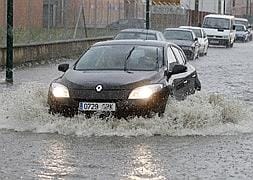 Un coche atraviesa la balsa de agua formada en la calle Vázquez de Menchaca