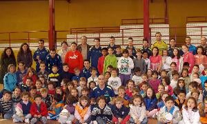 Los jugadores y el segundo entrenador del Caja Segovia posan con los niños de Otero de Herreros. / El Norte