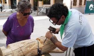 Una mujer observa como uno de los visitantes esculpe la madera. /El Norte