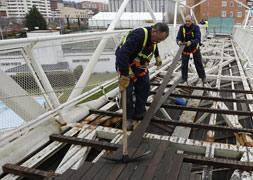 Los operarios desmontan las listas de madera del suelo de la pasarela / G. Villamil