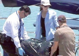 Los agentes transportan la cocaína intervenida en el casco del yate./ AFP