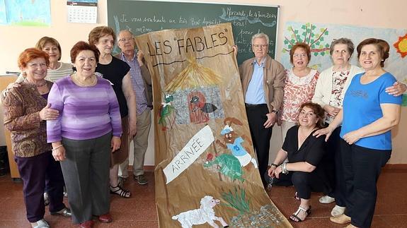 Un grupo de socios de Aulas 60 posa con un mural que han hecho en las clases de francés. 