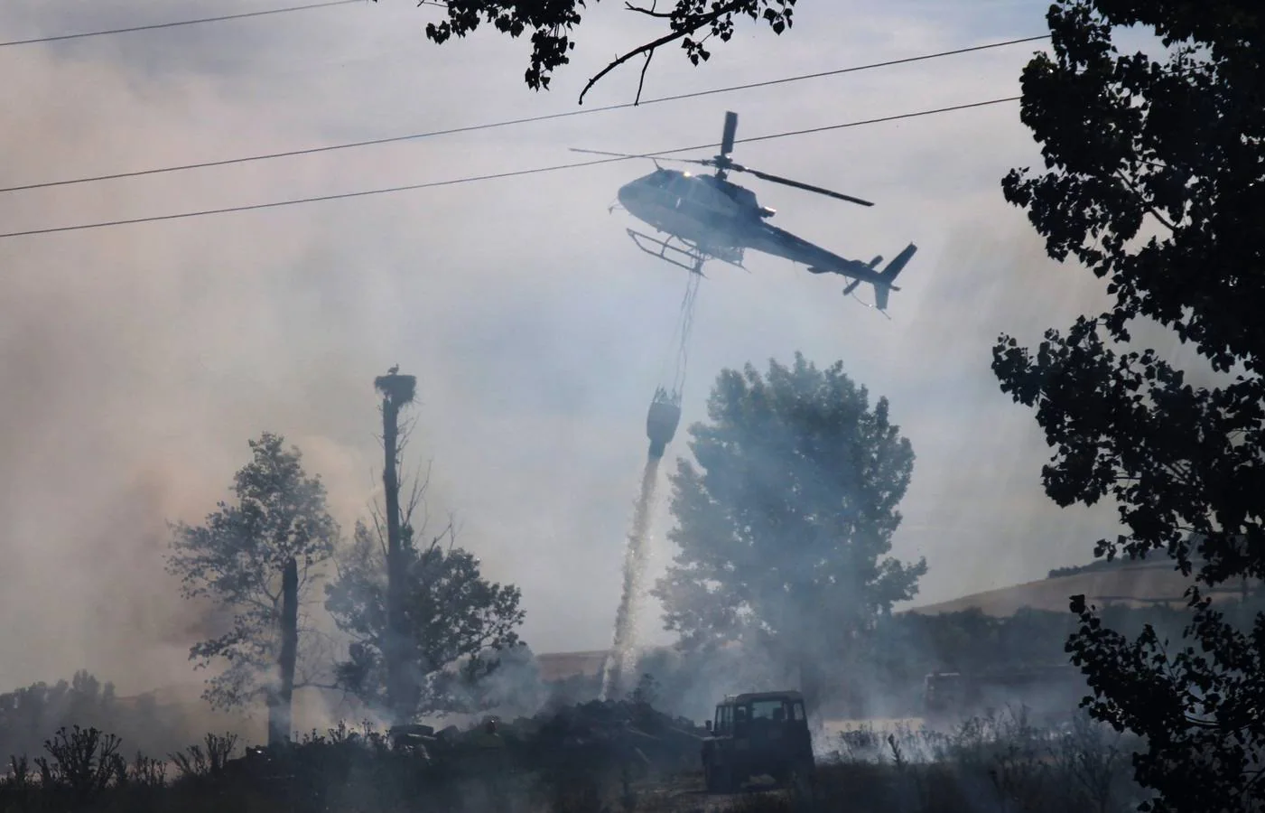 Un helicóptero lanza agua en el lugar del incendio