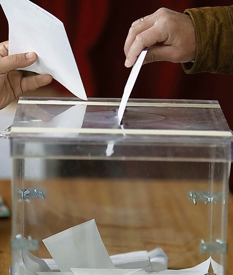 Un electoral deposita su voto en una urna.