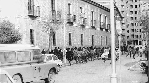 Un grupo de estudiantes de Medicina corre delante de un coche de la Policía