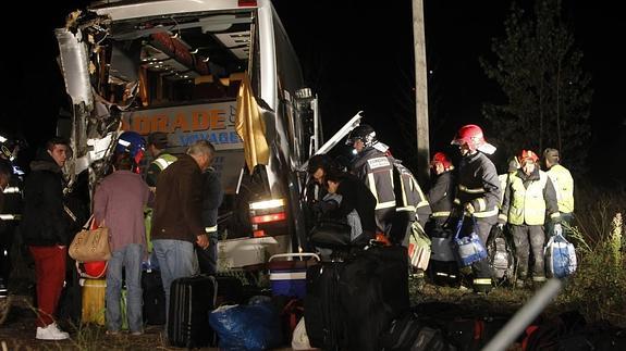 Los bomberos ayudan a los viajeros de uno de los autobuses siniestrados a sacar el equipaje.