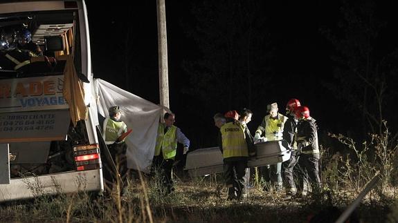 Guardias civiles y bomberos trasladan el féretro de una de las víctimas del accidente en Torquemada. 