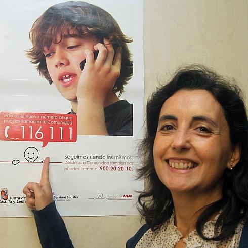 La delegada en Segovia de la Fundación Anar, Natalia Fernández, señala un cartel informativo de la organización.