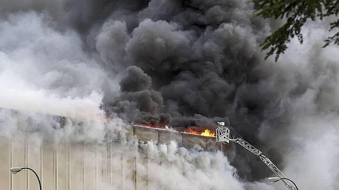 El intenso humo obliga a los bomberos a atacar el fuego con cañones controlados a distancia para evitar riesgos. 