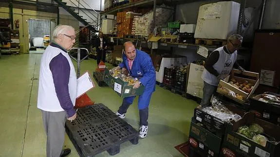 Tres voluntarios preparan víveres para su reparto en el Banco de Alimentos.