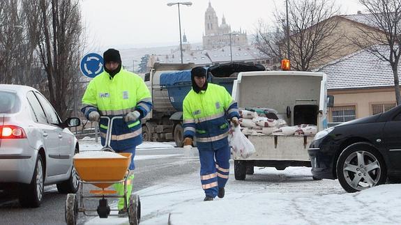 Operarios esparcen sal por la calzada en una pasada nevada sobre la ciudad del Acueducto.