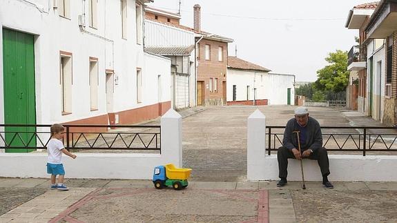 Un pequeño juega junto a una persona mayor en la localidad vallisoletana de Mayorga.