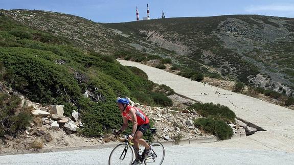 Un ciclista sube la cima de Las Guarramilas, con las antenas de la Bola del Mundo al fondo.
