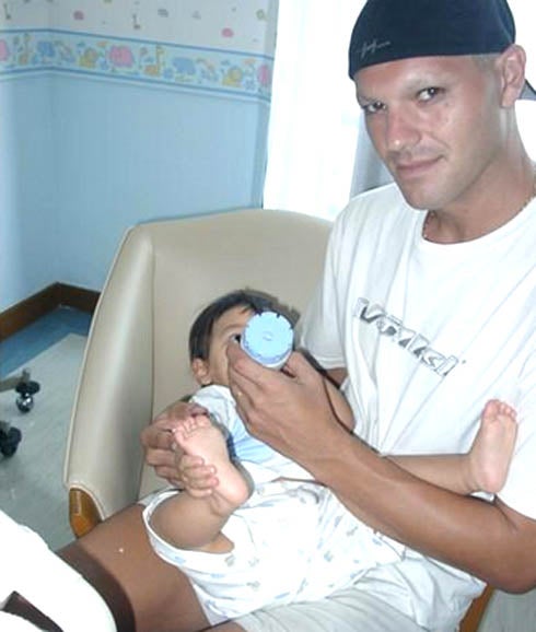 Frank Cuesta, convaleciente, da de comer a uno de sus hijos. 