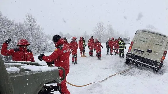 Efectivos de la UME  colocan las cuerdas para remolcar a una furgoneta que se había salido de la carretera por el hielo y la nieve en la provincia de León. 