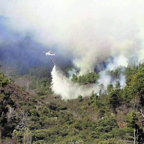 Un helicóptero lanza agua para sofocar las llamas. 