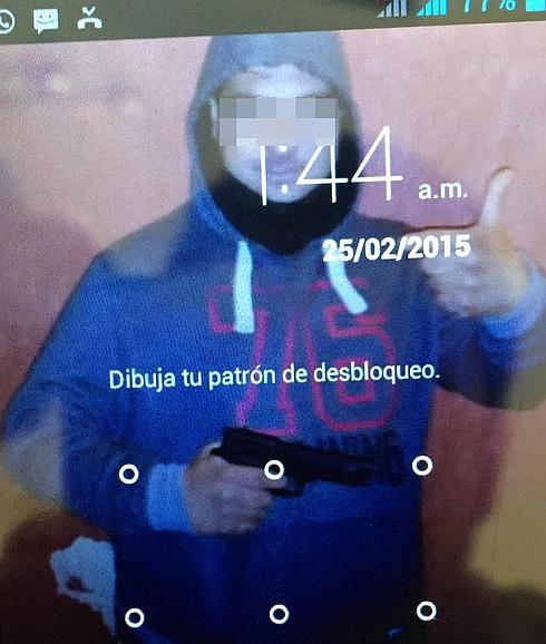 Fondo de pantalla del teléfono móvil sustraído, en el que se puede ver al principal acusado posando con una pistola en la mano. 