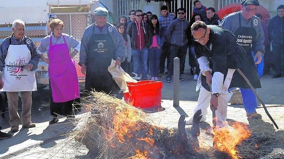 El matarife José Agustín Olaso, a la derecha, supervisa este sábado el proceso de chamuscado del cerdo.