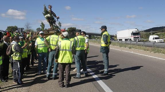 La Guardia Civil conversa con los vecinos, que portan el santo, en el acceso a la autovía. 
