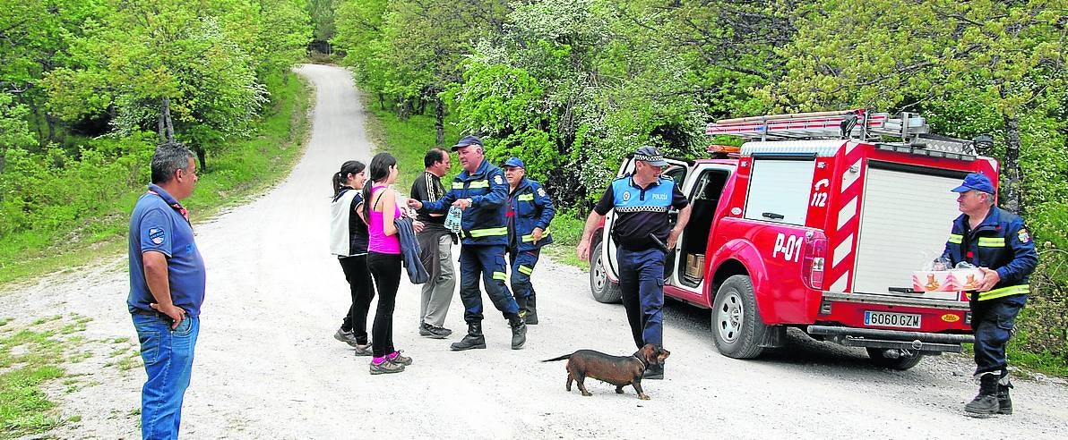 Algunos bomberos reparten agua y galletas a los participantes en la búsqueda. 