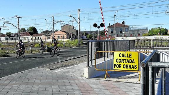 Varios ciclistas cruzan las vías del tren por la zona de Los Tres Pasos, donde Adif ha iniciado las obras para construir una pasarela elevada.