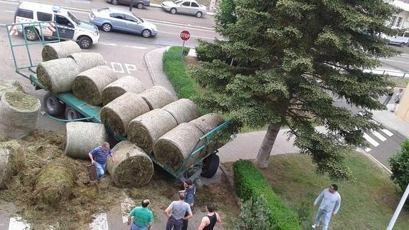 Rollos de hierba esparcidos por la calza junto al remolque.