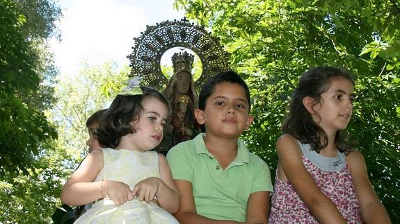 Tres niños desfilan junto a la talla de la Virgen del Henar en la romería de septiembre.