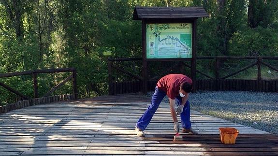 Un operario municipal trabaja en las tablas del pavimento de la senda.
