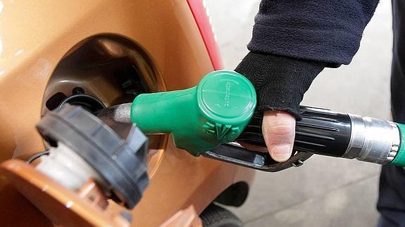 El empleado de una estación de servicio surte de gasolina un vehículo.