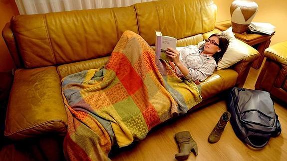 Una mujer lee en el sofá antes de dormir.