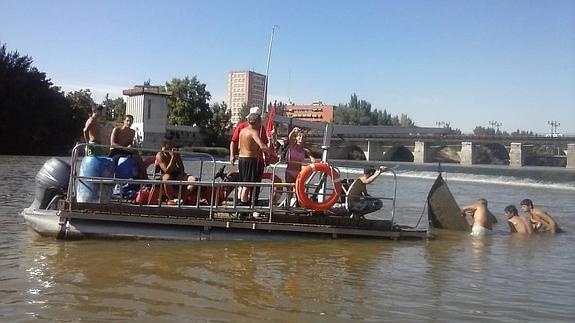 Integrantes de Amigos delPisuerga, junto a bañistas de Las Moreras, durante la recuperación de la barcaza hundida en el río. 