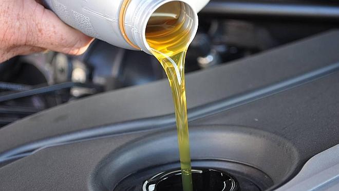 Automovilista vierte aceite en el motor de su coche. 