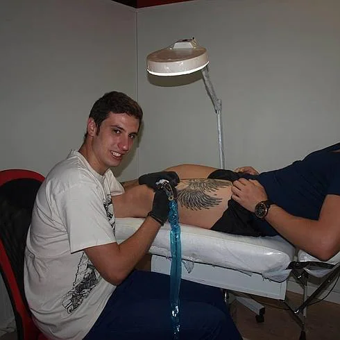 Iván tatúa una imagen en el muslo de un cliente 
