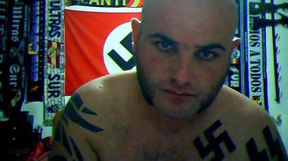 M.A.R.G., en su cuarto, rodeado de simbología nazi y armas y munición colgadas de las paredes.