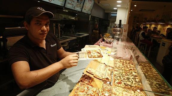 Uno de los empleados de Papizza muestra un décimo de lotería no premiado y la porción de pizza de regalo. 