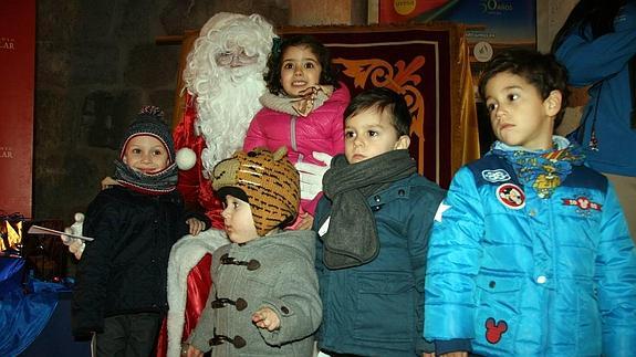 Unos niños rodean a Papá Noel e su escala cuellarana. 
