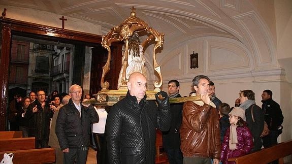 Miembros de la Cofradía del Niño de la Bola portan en andas la imagen, ayer, ante la imposibilidad de sacarla a la calle por la lluvia. 