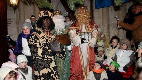 Los tres Reyes Magos, rodeados de niños en una de las paradas del cortejo.