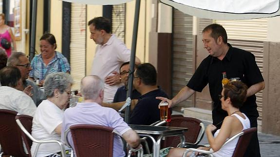 Un camarero sirve unas bebidas a los clientes en una terraza.