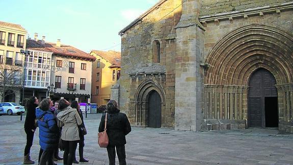 Un grupo de turistas, ante la Colegiata de San Miguel en Aguilar de Campoo.