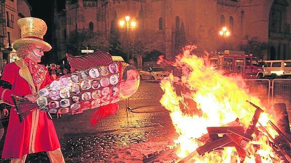 Un componente de La Semifusa arroja a la pira la sardina elaborada por la comparsa, con fotos y caricaturas de diversos personajes políticos. 