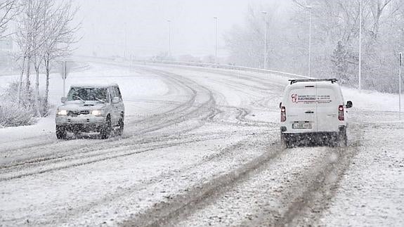 Dos vehículos circulan entre la nieve, en la carretera de Aguilar al polígono de Villallano.