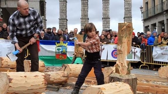 Javier, de seis años, corta un tronco en vertical con ayuda de su padre.