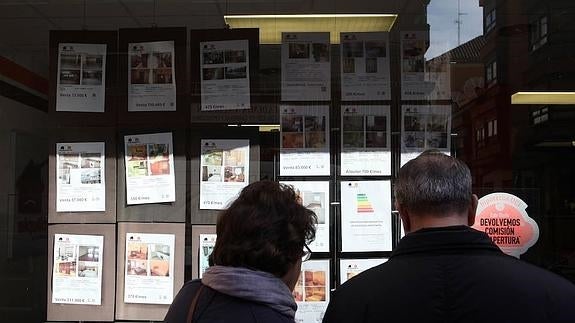 Una pareja observa los anuncios de una inmobiliaria en Valladolid. 