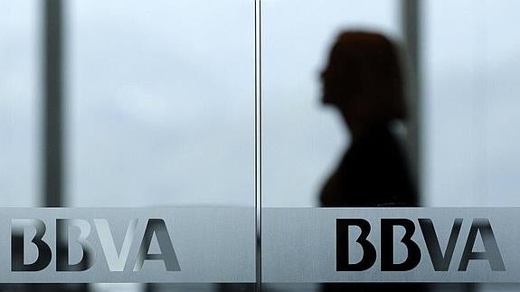 empleada de un oficina del BBVA tras los cristales de la puerta de entrada. / REUTERS