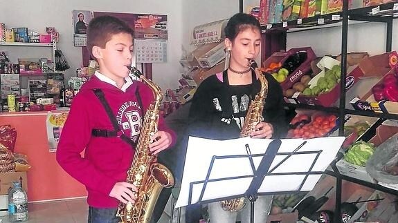  Dos alumnos de la Escuela de Música de Nava de la Asunción interpretan la partitura en el interior de un comercio de la localidad. F. de la Calle