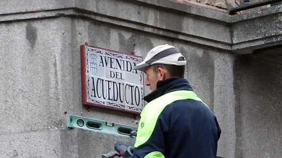 Un operario municipal instala la nueva placa en la avenida del Acueducto. 