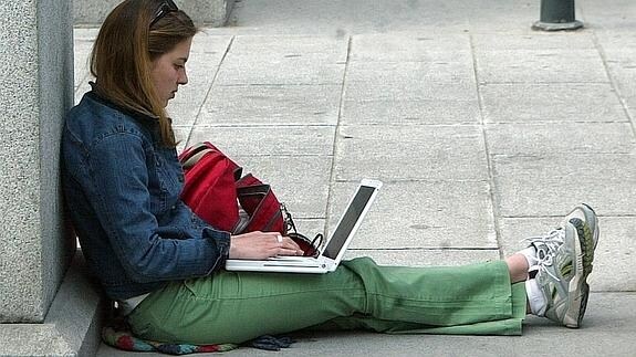Una chica consulta el ordenador en una calle de Segovia.