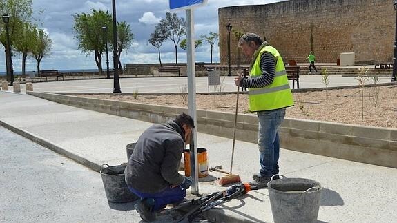 Dos trabajadores de la cuadrilla de obras del Ayuntamiento de Toro colocan una señal junto al centro de recepción de visitantes de Las Edades en el Alcázar
